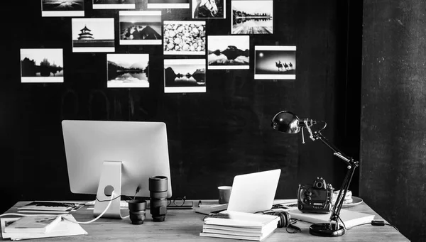 Fotos en la pared, ordenador portátil y cámara en la mesa — Foto de Stock