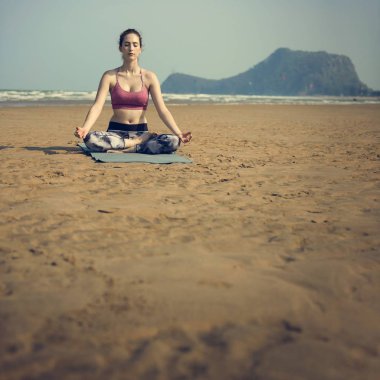 Kumsalda yoga yapan bir kadın.