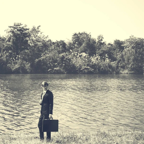 Homme d'affaires debout sur la rive de la rivière — Photo