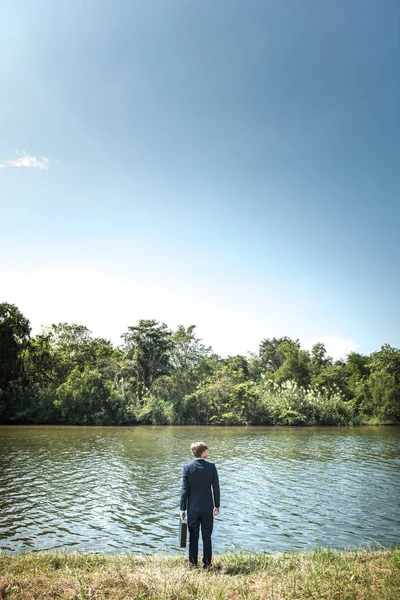 Empresario de pie en la orilla del río — Foto de Stock