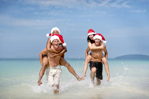Пари в Санта капелюхів веселяться на пляжі — стокове фото