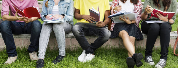 Diverse students sit at park