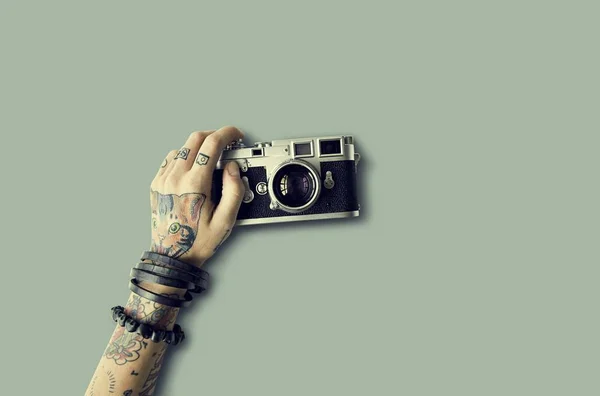 Hand in tattoos holds Photo Camera — Stock Photo, Image