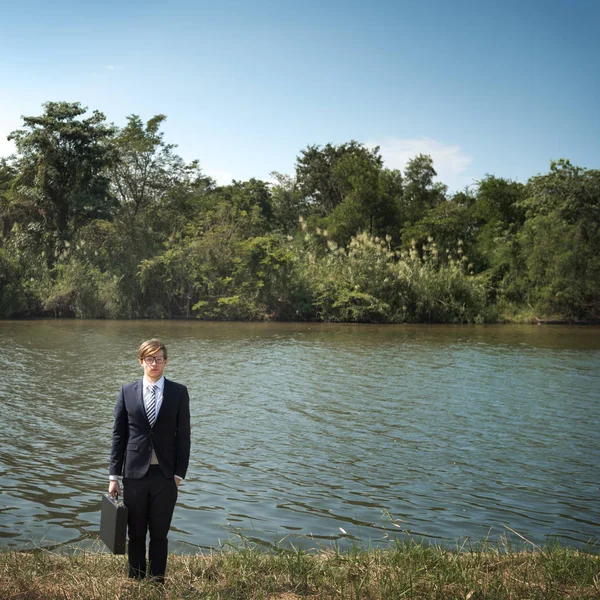 Empresario de pie en la orilla del río — Foto de Stock