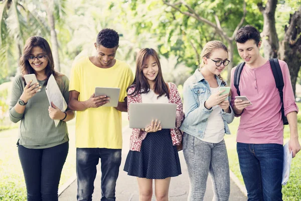 Vrienden lopen en het gebruik van digitale apparaten — Stockfoto