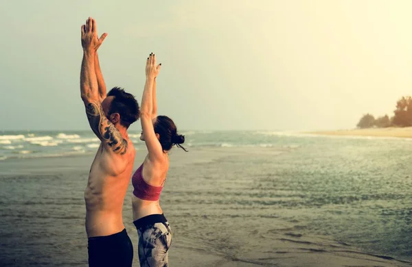 Par som gör yoga på stranden — Stockfoto