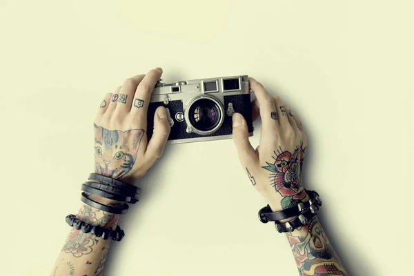Mãos em tatuagens detém câmera fotográfica — Fotografia de Stock