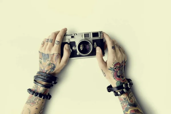 Manos en tatuajes sostiene cámara fotográfica — Foto de Stock