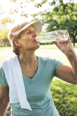 Yaşlı kadın su içiyor.