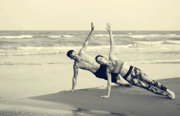 Par som gör yoga på stranden — Stockfoto