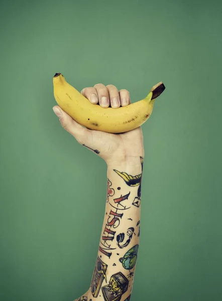 Mano nei tatuaggi tiene banana — Foto Stock