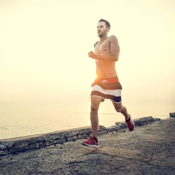 Hombre deportivo corriendo en la playa — Foto de Stock
