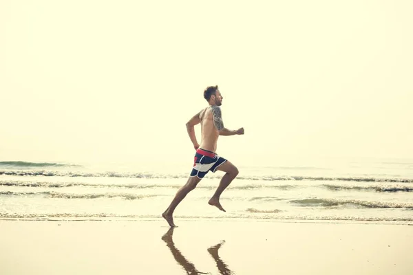 Hombre deportivo corriendo en la playa — Foto de Stock