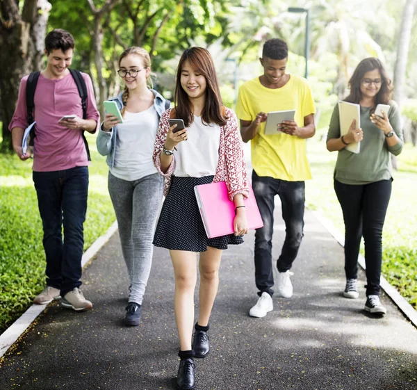 Amici che camminano e utilizzano dispositivi digitali — Foto Stock