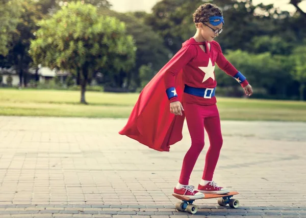 Супергеройский мальчик катается на скейтборде — стоковое фото