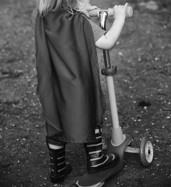 Superheldenjunge fahren mit dem Motorroller — Stockfoto