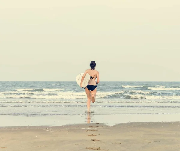 Mujer con tabla de surf en la playa — Foto de Stock