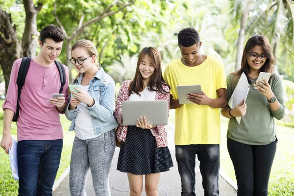 Amici che camminano e utilizzano dispositivi digitali — Foto Stock