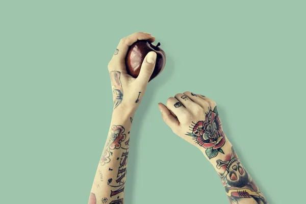 Mãos em tatuagens contém maçã — Fotografia de Stock