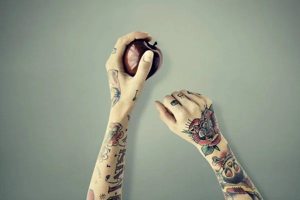 Ruce v tetování drží jablko — Stock fotografie