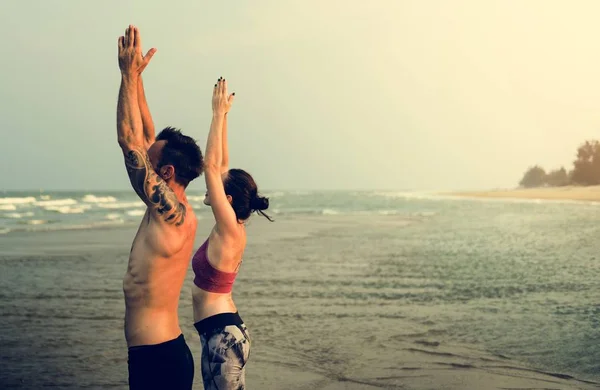 Par som gör yoga på stranden — Stockfoto