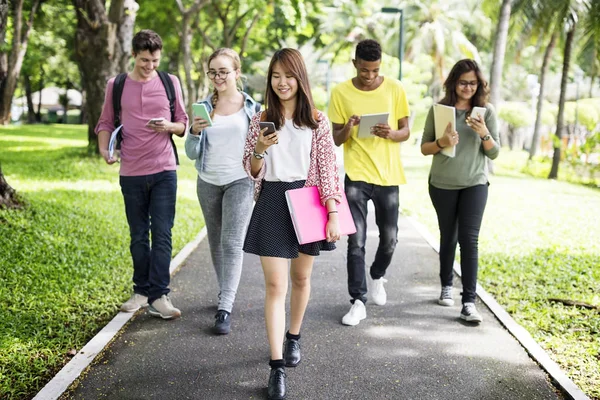 Amici che camminano e utilizzano dispositivi digitali — Foto Stock