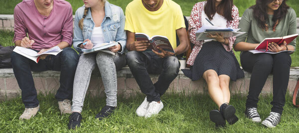 Diverse students sit at park