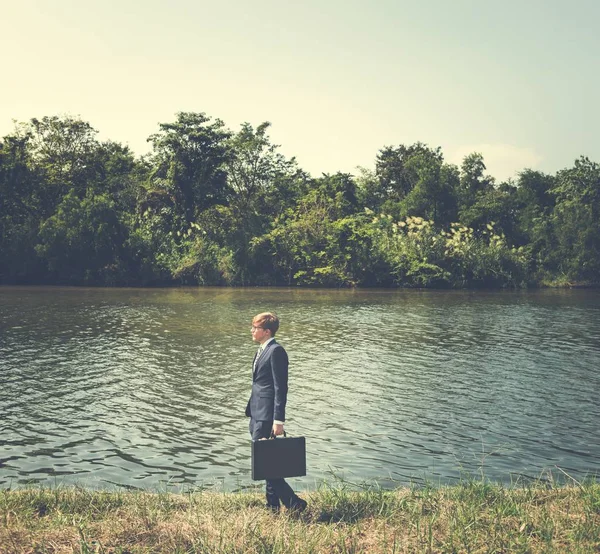 Homme d'affaires debout sur la rive de la rivière — Photo