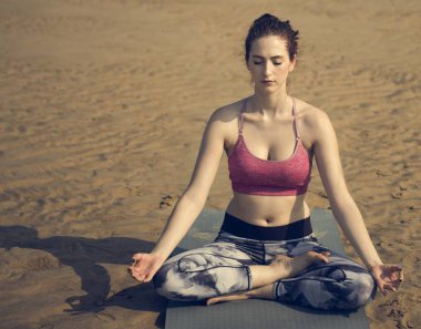 Kumsalda yoga yapan bir kadın.
