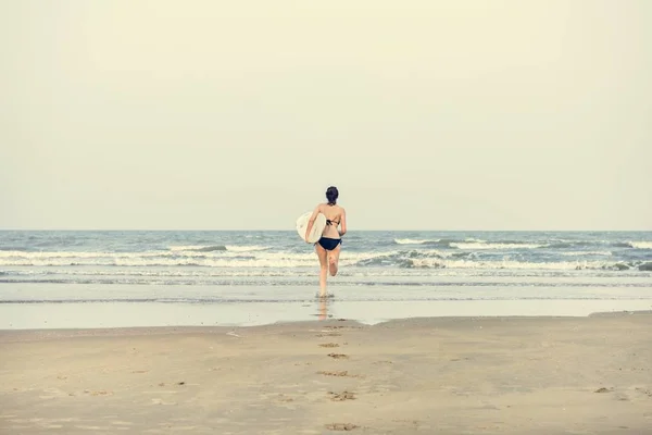 Mujer con tabla de surf en la playa —  Fotos de Stock