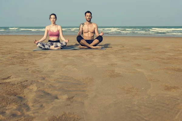 Par som gör yoga på stranden — Stockfoto