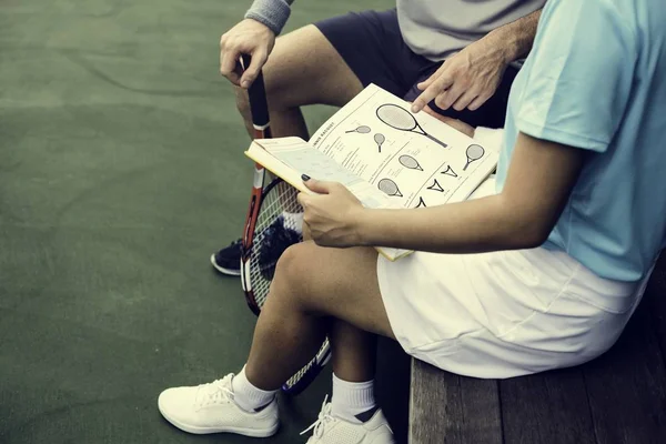 Девочка и тренер читает книгу по теннису — стоковое фото