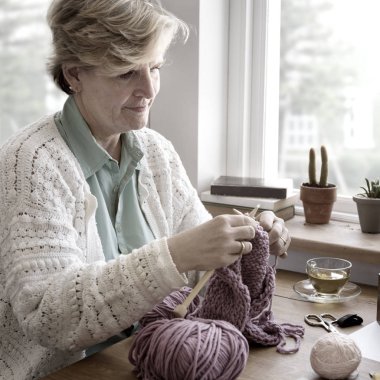 Kadın evde örgü örüyor.