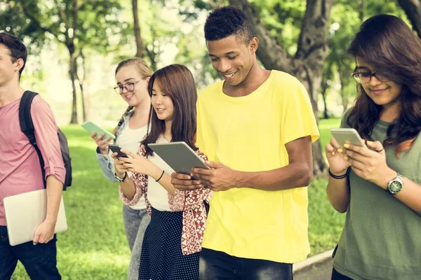 Amici che camminano e utilizzano dispositivi digitali — Foto Stock