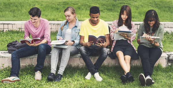 Diverse students sit at park