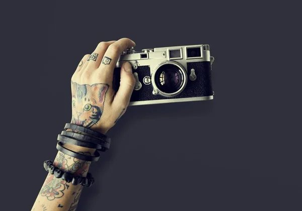 Ręka w tatuaże trzyma aparat fotograficzny — Zdjęcie stockowe
