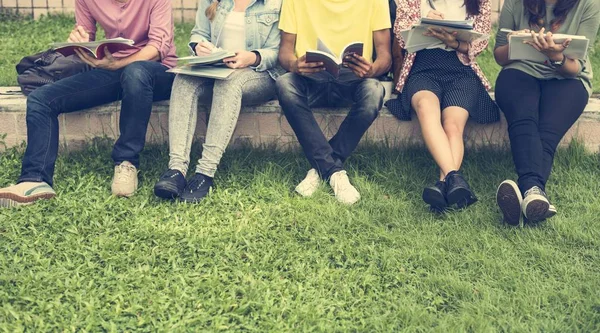 Diversos estudantes sentam-se no parque — Fotografia de Stock