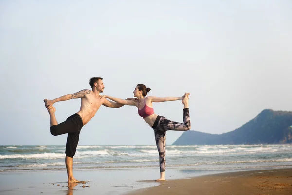 Pareja haciendo yoga en la playa — Foto de Stock