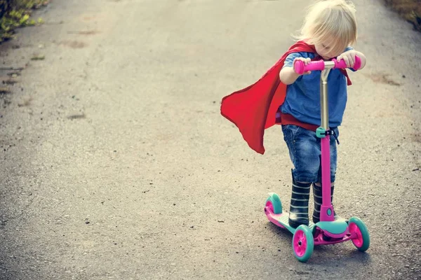 超级英雄男孩骑滑板车 — 图库照片
