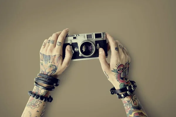 Mains dans les tatouages tient appareil photo — Photo
