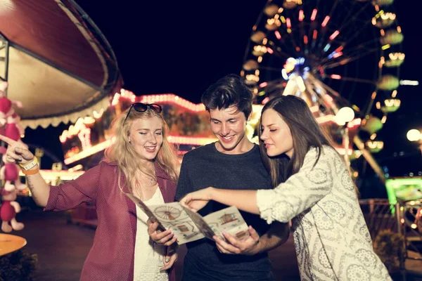 Amigos em parque de diversões com mapa — Fotografia de Stock