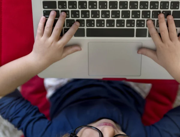 Petite fille en lunettes à l'aide d'un ordinateur portable — Photo