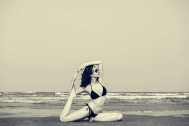 Kumsalda yoga yapan bir kadın.