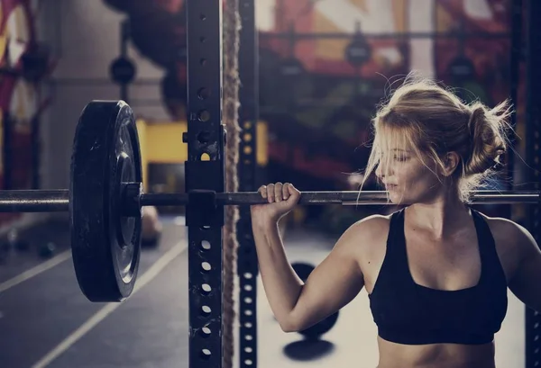 Vrouw werpt bar in sportschool — Stockfoto