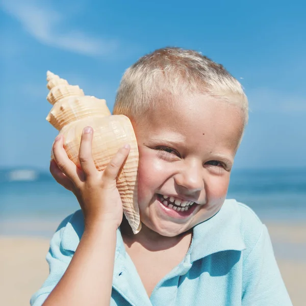 Petit garçon écoute coquille — Photo