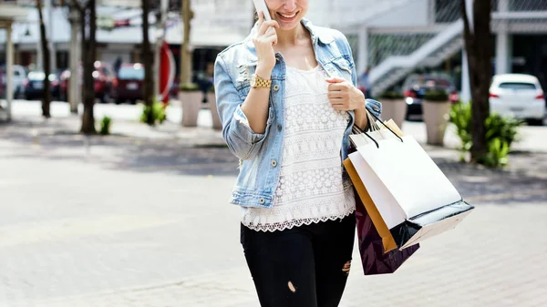 Woman with shopping bag using smartphone — Stock Photo, Image