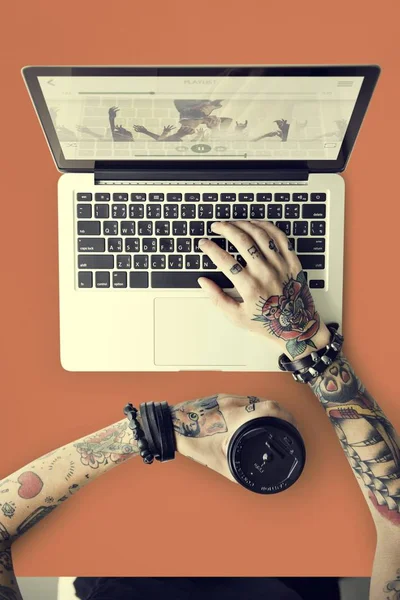 Mãos em tatuagens digitando no laptop — Fotografia de Stock