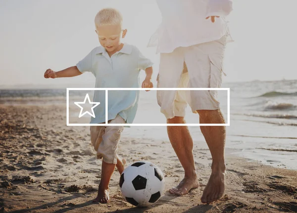 Far och son som spelar fotboll på stranden — Stockfoto