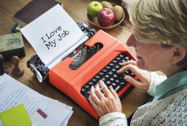 senior woman writing on typewriter machine  clipart