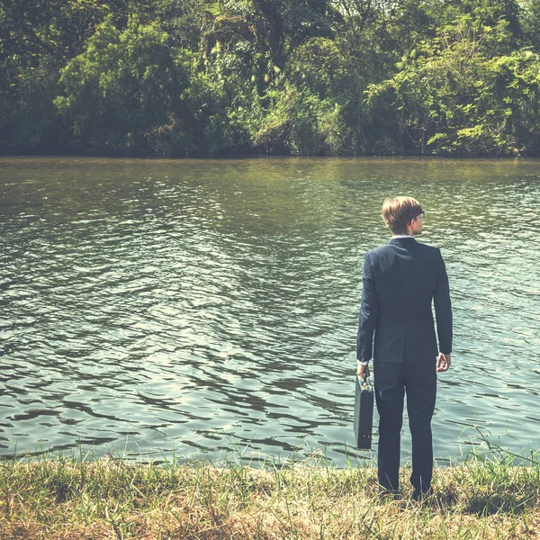 Empresario de pie en la orilla del río . — Foto de Stock